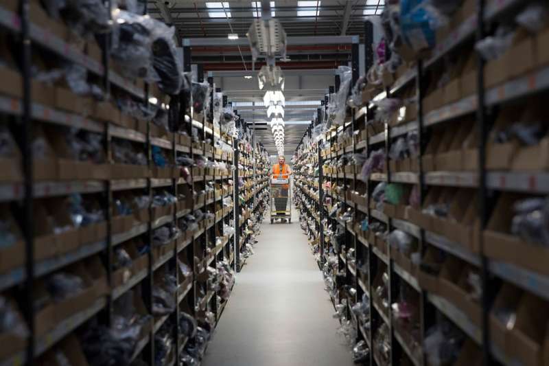 An employee pushes a cart as he processes a customer order ahead of shipping at one of Amazon.com Inc.'s fulfillment centers in Rugeley, U.K., on Monday, Dec. 2, 2013. Online retailers in the U.K. are anticipating their busiest day as shoppers flush with end-of-month pay-checks seek Christmas deals on the Web. Photographer: Simon Dawson/Bloomberg via Getty Images