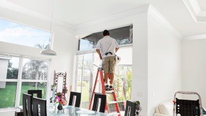 man on ladder replacing window