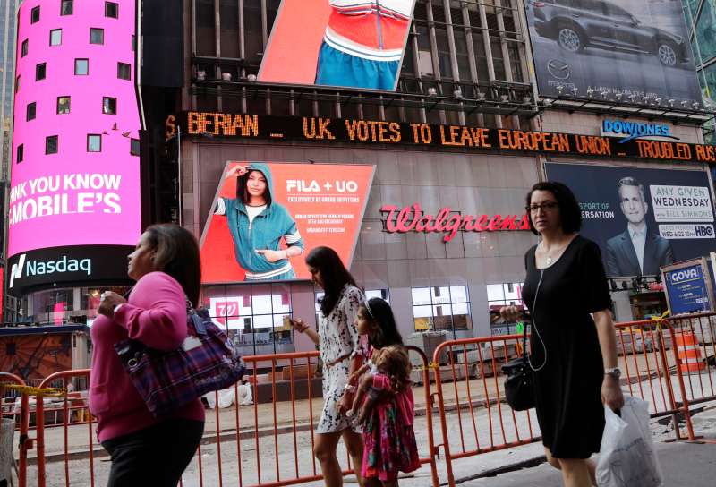 People walk past a news ticker that reads U.K. Votes to Leave European Union, Friday, June 24, 2016, in New York's Times Square. Britain voted to leave the European Union after a bitterly divisive referendum campaign, sending global markets plunging, casting British politics into disarray.