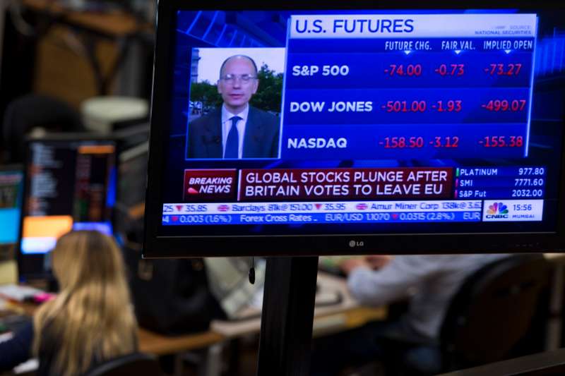 A TV screen shows global stocks plunging following the British Brexit vote as traders, background, work at the Euronext Amsterdam Stock Exchange, Netherlands, Friday, June 24, 2016. The British vote to leave the EU shook up financial markets around the globe on Monday, leading to sharp falls in stocks and the British pound.