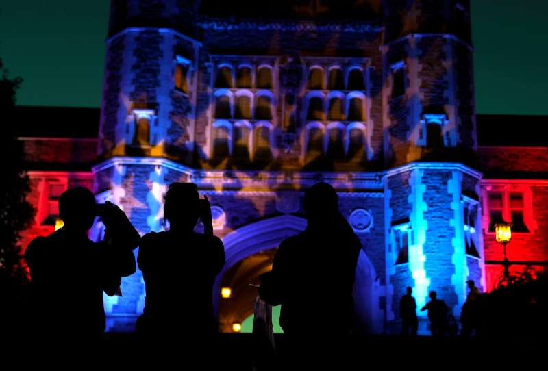 People stop to take photos of Brookings Hall, which is lit up in a patriotic theme, as preparations continue ahead of the second presidential debate at Washington University in St. Louis, Thursday, Oct. 6, 2016. The town hall debate between Republican presidential nominee Donald Trump and Democratic presidential nominee Hillary Clinton is set for this Sunday.