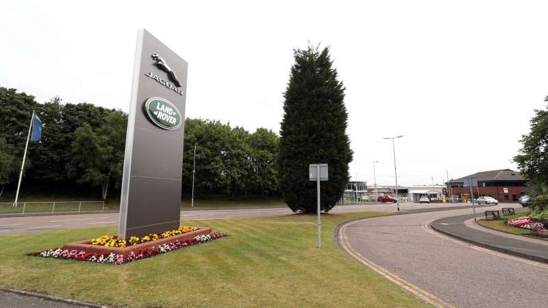 The Jaguar and Land Rover company logos sit on a sign at the entrance to Tata Motors Ltd.'s Jaguar Land Rover vehicle manufacturing plant in Solihull, U.K., on Wednesday, July, 15, 2015. Jaguar Land Rover, the U.K. luxury-car unit of Tata Motors Ltd., cut its sales targets and prices in China amid slowing demand in the world’s largest auto market. Photographer: Chris Ratcliffe/Bloomberg