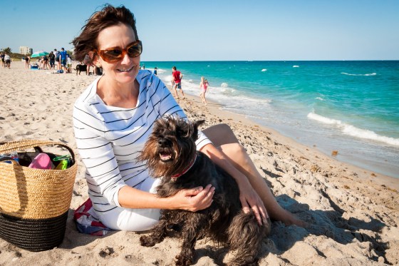 Woman sitting in the sand with her dog at the Spanish River Dog Park in Boca Raton Florida