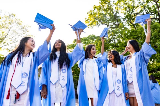 Five college graduates from The University of North Carolina at Chapel Hill raising their cap