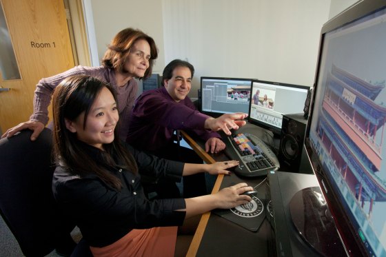 One student and two teachers go over a video on a computer at Bryant University