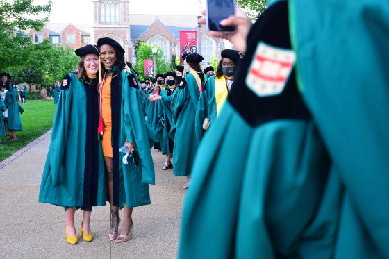 Two students pose for a photo during their graduation ceremony at Washington University in St. Louis